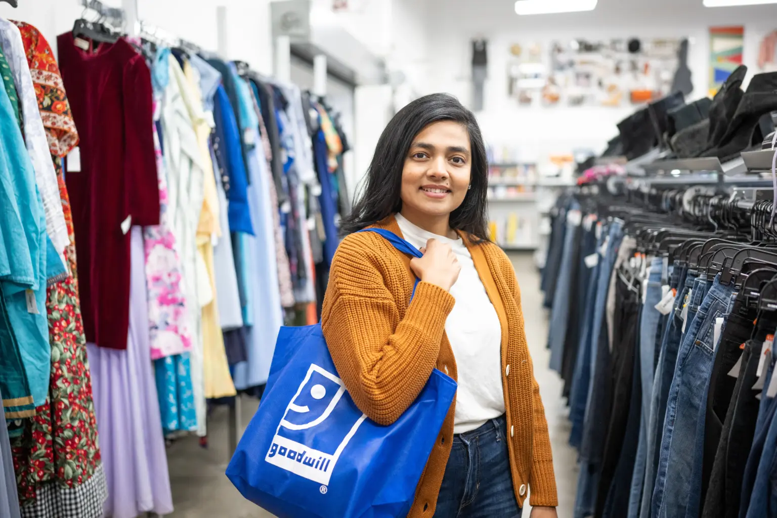 Goodwill shopper browsing clothing racks.